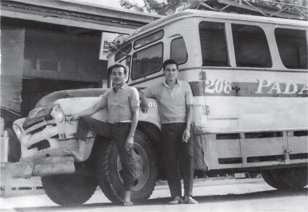 Black-and-white photo of Nicanor "Momoy" Gabunada Sr. and his bus conductor leaning against the front of their passenger bus, number 208.